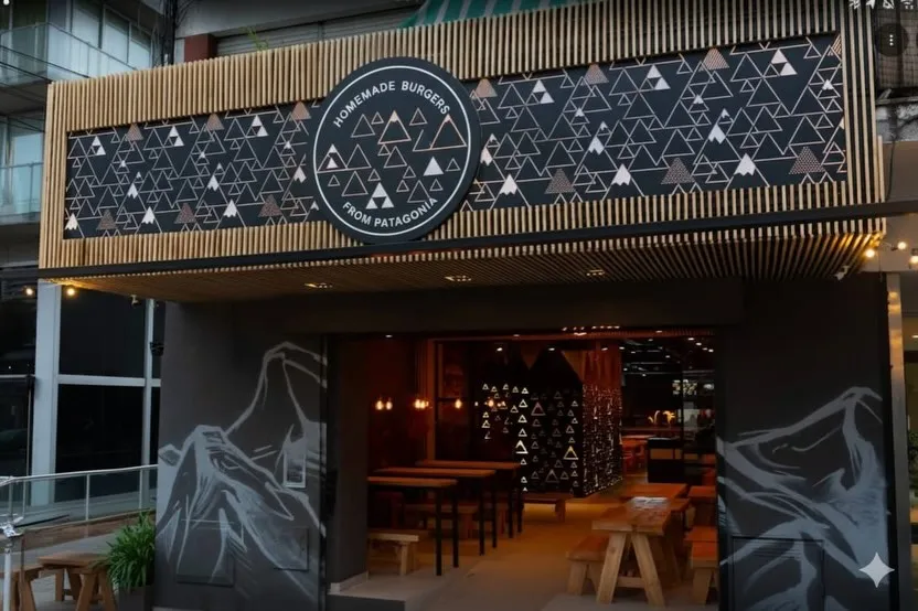 Entrada de Weiss con mural de montañas de la Patagonia y bancos de madera
